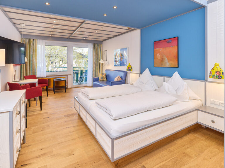 Das gemütliche Bett im Doppelzimmer Deluxe umringt von stilvoller Einrichtung