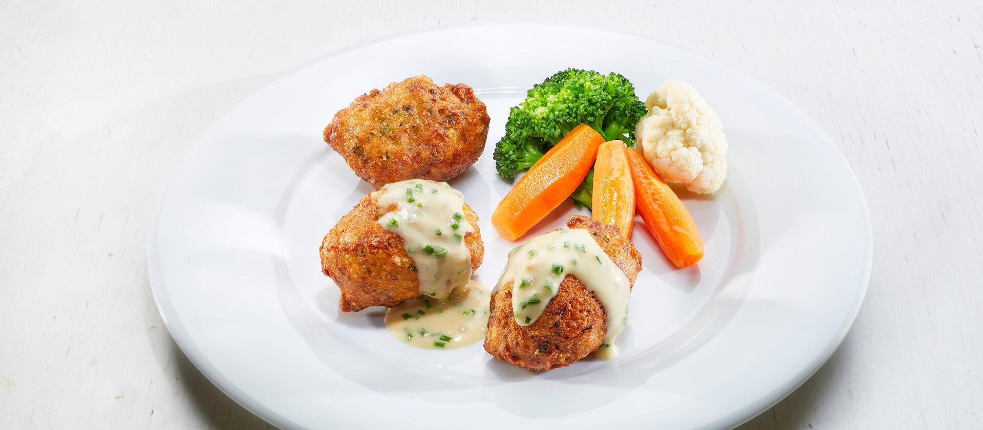 Auf einen Teller liegen Bergkäsekrapfen schön angerichtet und bereit um serviert zu werden.