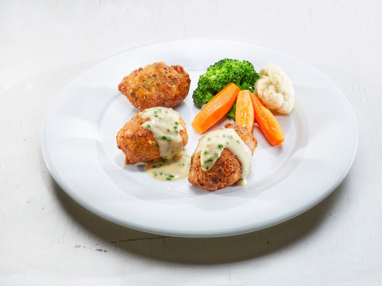 Auf einen Teller liegen Bergkäsekrapfen schön angerichtet und bereit um serviert zu werden.