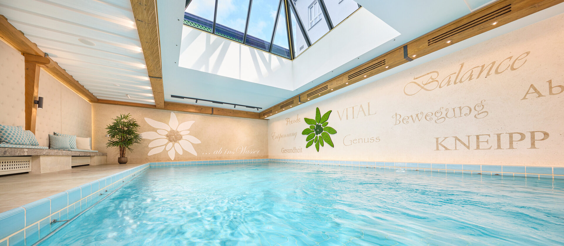 Das Wasser im gro&szlig;en Innenpool wirkt durch das gro&szlig;e Dachfenster bei Tag t&uuml;rkis