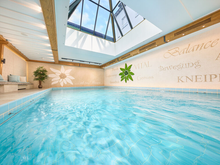 Das Wasser im großen Innenpool wirkt durch das große Dachfenster bei Tag türkis