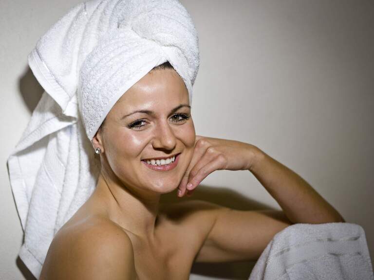 Eine entspannte Frau mit Handtuchturban strahlt Glück nach einer Wellness-Behandlung aus.