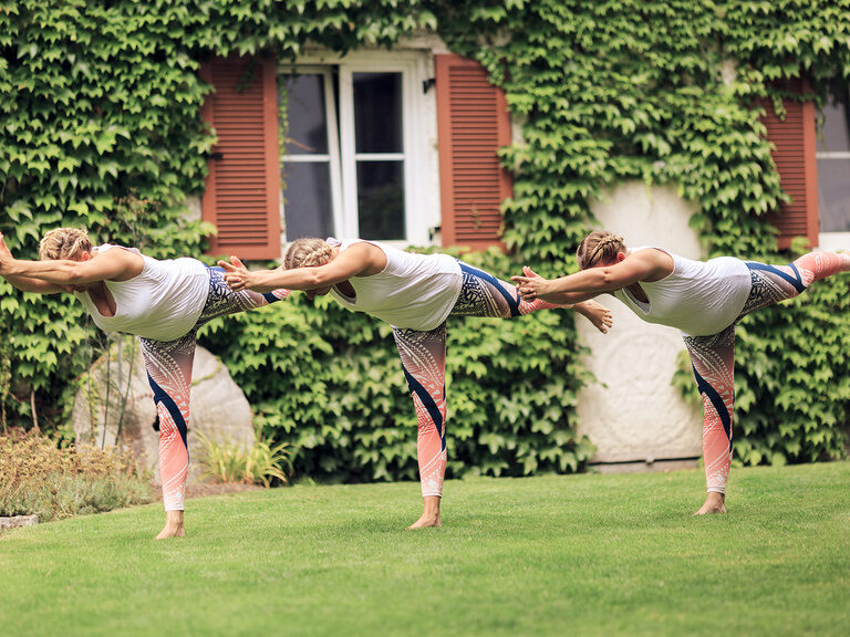 Drei Frauen machen Yoga-Positionen im Garten